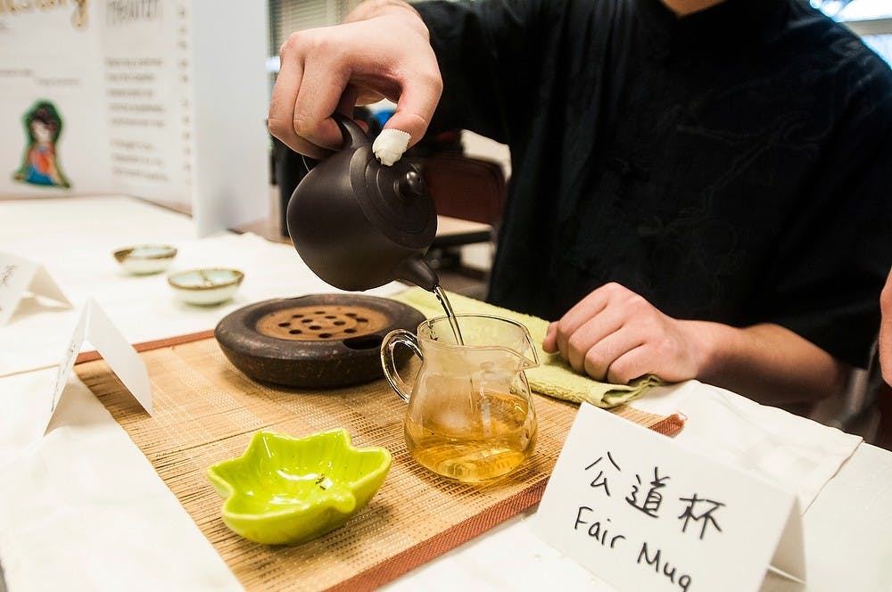 <p>Supply chain sophomore Qian Zhang pours tea for guests March 28, 2014 at a tea expo in Hubbard Hall put on by the Oriental Leaves Chinese Tea Art Club. The expo offered tastings of teas imported directly from China. Erin Hampton/The State News</p>