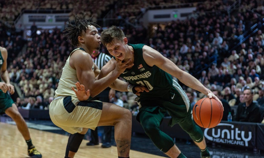 <p>Senior guard Matt McQuaid (20) powers past Purdue guard Carsen Edwards. The Spartans fell to the Boilermakers, 73-63.</p>
