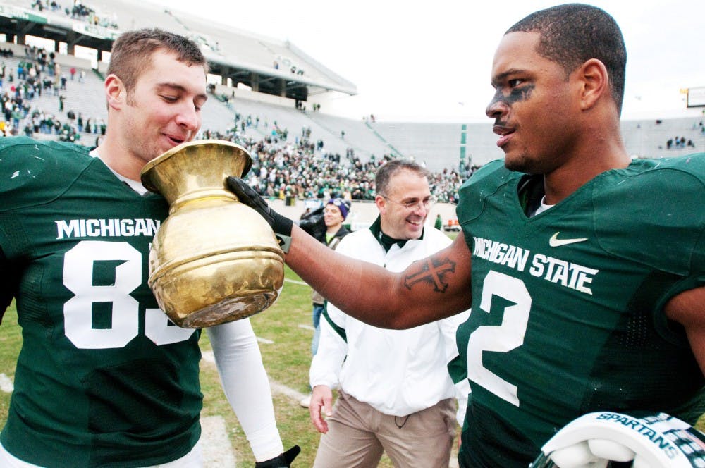 Sophomore defensive end William Gholston holds the Old Brass Spittoon for senior tight end Garrett Celek as he spits into it after Michigan State defeated Indiana on Senior Day. The Spartans defeated the Hoosiers, 55-3, on Saturday afternoon at Spartan Stadium. Josh Radtke/The State News