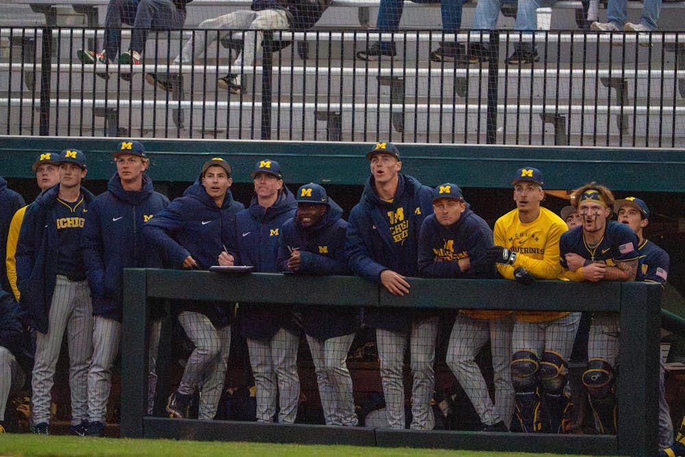 Michigan players watch from the dugout, reacting to the play during Michigan’s game against Michigan State at Jeff Ishbia Field at McLane Stadium in East Lansing, Mich., on Friday, April 10, 2026.