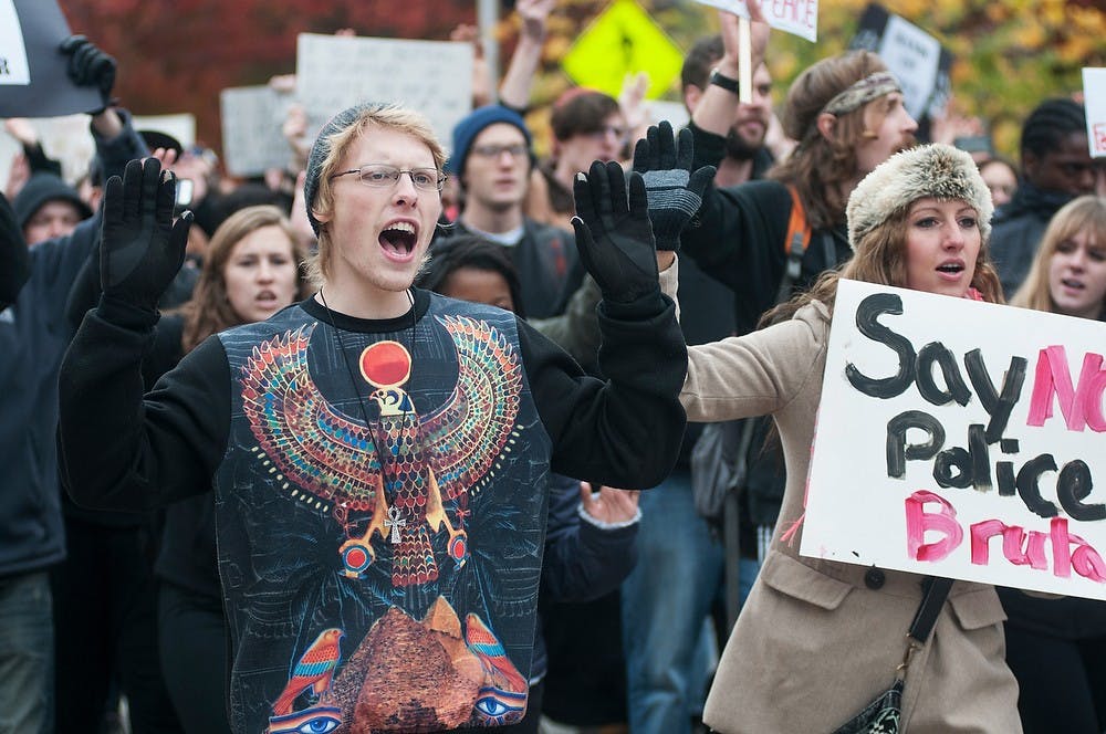 <p>Chemical engineering senior Andrew Smith and animal science junior Shaina Alvesteffer protest on Oct. 22 2014, near Olin Health Center. Protesters marched to the police department from the Beaumont Tower to support Michael Brown, who was shot and killed by police in Ferguson, Mo. Aerika Williams/The State News</p>