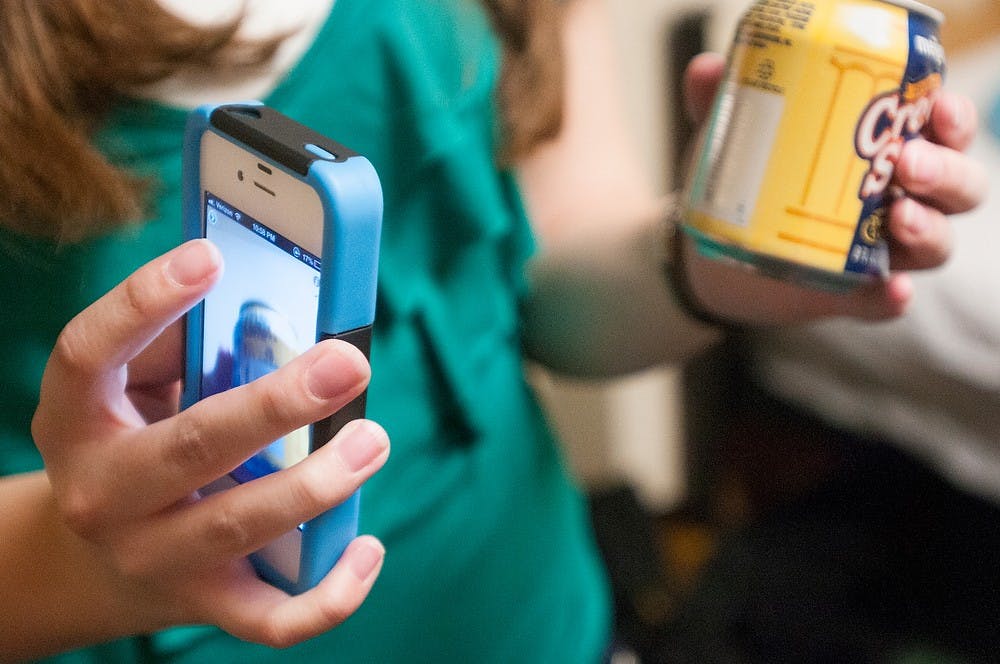 	<p>Computer science sophomore Jordyn Castor uses an app on her cell phone to read a pop can in her dorm room in Case Hall on Monday, April 15, 2013. Many different apps are accessible and can read bills, food brands, and perform many other functions. Danyelle Morrow/The State News</p>