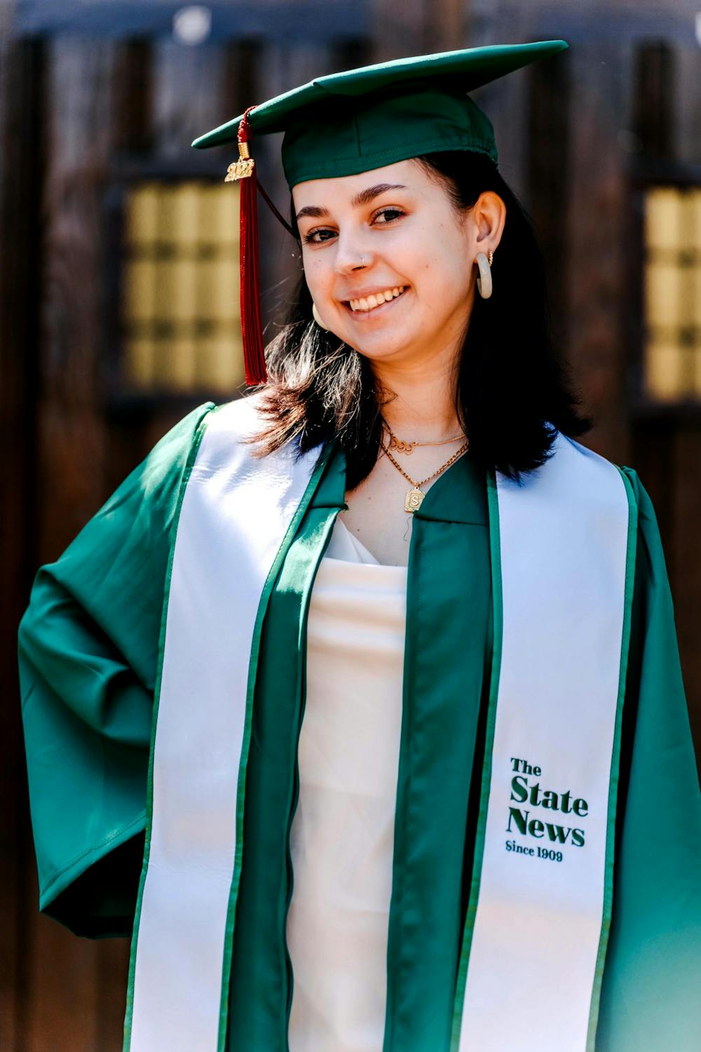 <p>The State News&#x27; women&#x27;s basketball beat reporter and Michigan State journalism senior Sara Tidwell stands in her cap and gown in front of the Beaumont Tower.</p>