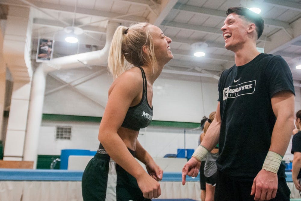 Advertising junior Olivia Valley, left, laughs with psychology senior Jacob Jean, right, during the MSU Cheerleading Team practice on Feb. 28, 2017 at Jenison Field House. 