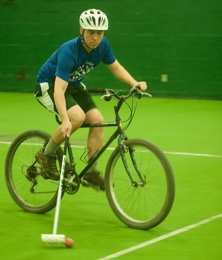 <p>Graduate student Eddie Glayzer shoots the ball during a game of bike polo Feb. 20, 2015, at IM Sports West. A group meets every Friday during the winter to play bike polo in order to get some exercise and have some fun. Alice Kole/The State News</p>