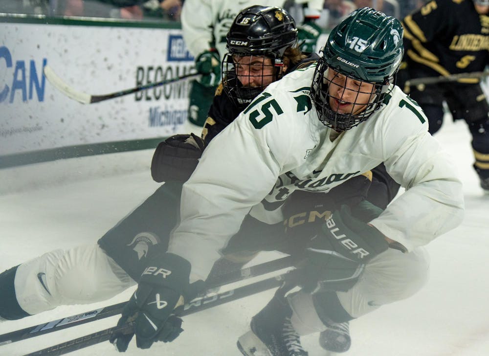 Michigan State University junior forward Charlie Stramel (15) and Lindenwood University junior defender Joe Prouty (15) players fight for the puck in Munn Ice Arena on Dec. 1, 2024. The Spartans beat the Lions, 2-0, in a shutout.