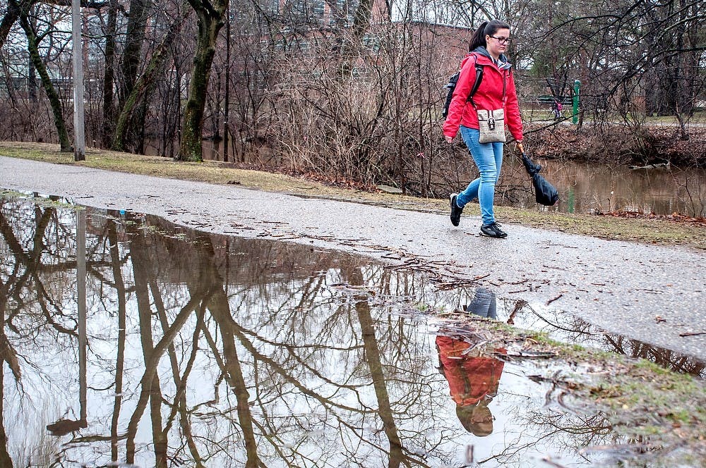 	<p>Psychology freshman Laura Bizzarri walks past a puddle behind <span class="caps">MSU</span> Ramp 2 near Red Cedar River April 11, 2013. Light, rain and occasional showers hovered in East Lansing, and the flood advisory for Red Cedar River remained in effect as of press time April 11. </p>