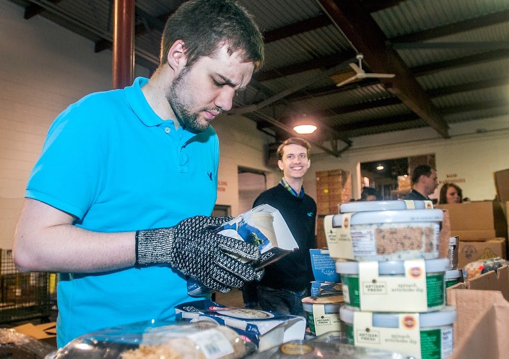	<p>Hans Schroeder, Lansing Community College student and member of the Student Leadership Academy, sorts out different types of food Wednesday, March 27, 2013, at the Greater Lansing Food Bank Warehouse, 2116 Mint Road, in Lansing. Donation money raised by the We Sing for Food project goes to the food bank where volunteers help distribute it. Adam Toolin/The State News</p>