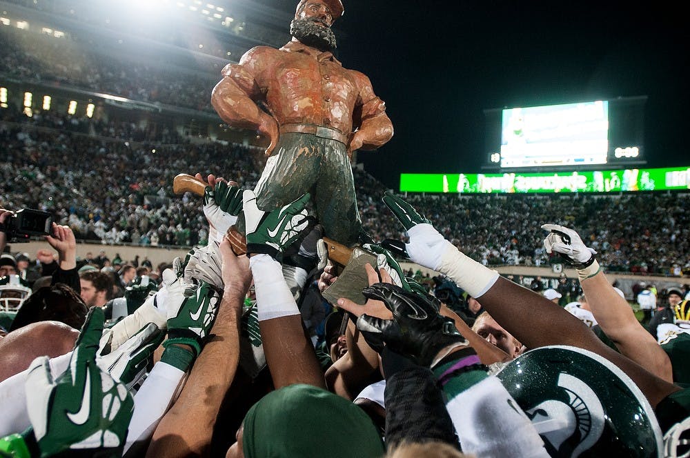 <p>The players celebrate with the Paul Bunyan trophy after the game against Michigan on Nov. 2, 2013, at Spartan Stadium. The Spartans defeated the Wolverines, 29-6. Khoa Nguyen/The State News</p>