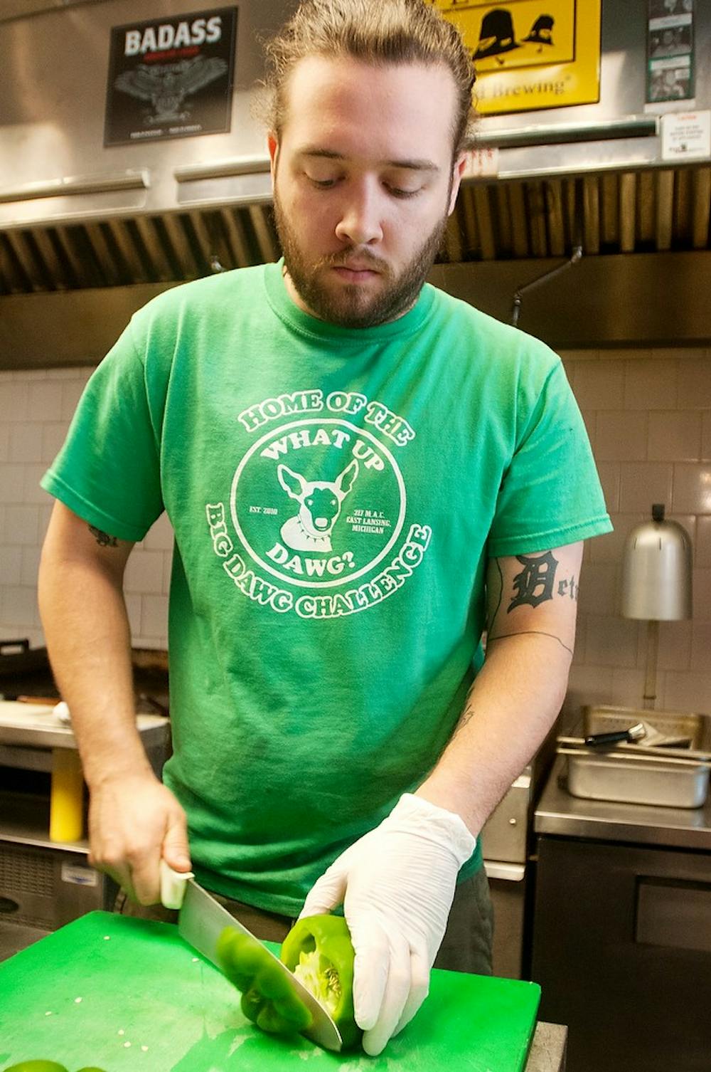 	<p>Anthropology senior Andrew Jasmer cuts up a green pepper June 12, 2013 at What Up Dawg?, 317 M.A.C Avenue. The restaurant offers a wide variety of hot dogs, including coney dogs.  Weston Brooks/The State News</p>