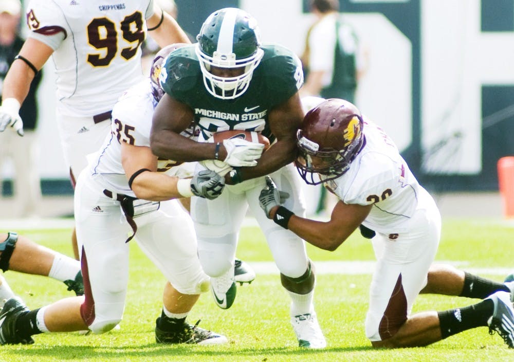 Junior running back Larry Caper maintains possession of the ball as Central Michigan linebacker Mike Kinville, left, and defensive back Jarret Chapman, right, attempt to tackle him during Saturday's game at Spartan Stadium. Caper scored one of the Spartan's six touchdowns, leading to their 45-7 victory over the Chippewas. Lauren Wood/The State News