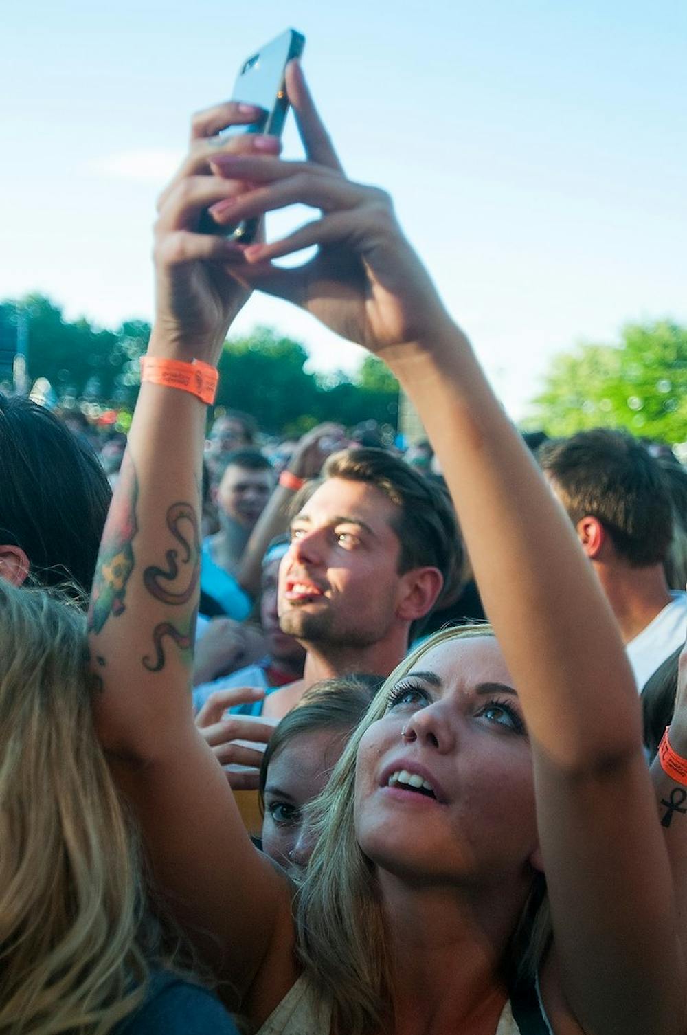<p>Kenosha, Wisc., resident Miranda Bentz takes a photo of The Hold Steady as they perform at the Auto Value Main Stage on July 8, 2014, at Adado Riverfront Park in downtown Lansing. Common Ground Music Festival is in its 15th year of performances. Danyelle Morrow/The State News</p>