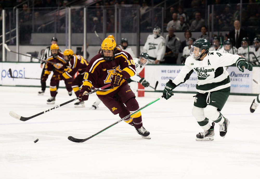 Junior defenseman Nash Nienhuis (4) tries to get the puck off of University of a Minnesota player at Munn Ice Arena on Dec. 2, 2022. The Spartans lost to the Gophers with score 5-0. 