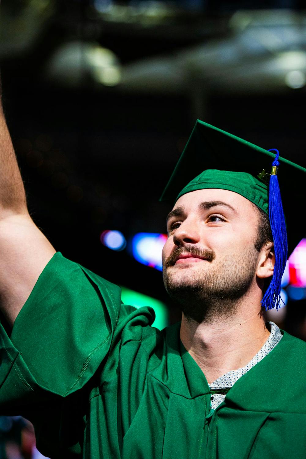 An MSU alumnus reaches up toward the mezzanine after receiving his diploma during the fall 2024 commencement ceremony at the Breslin Center on Dec. 14, 2024.