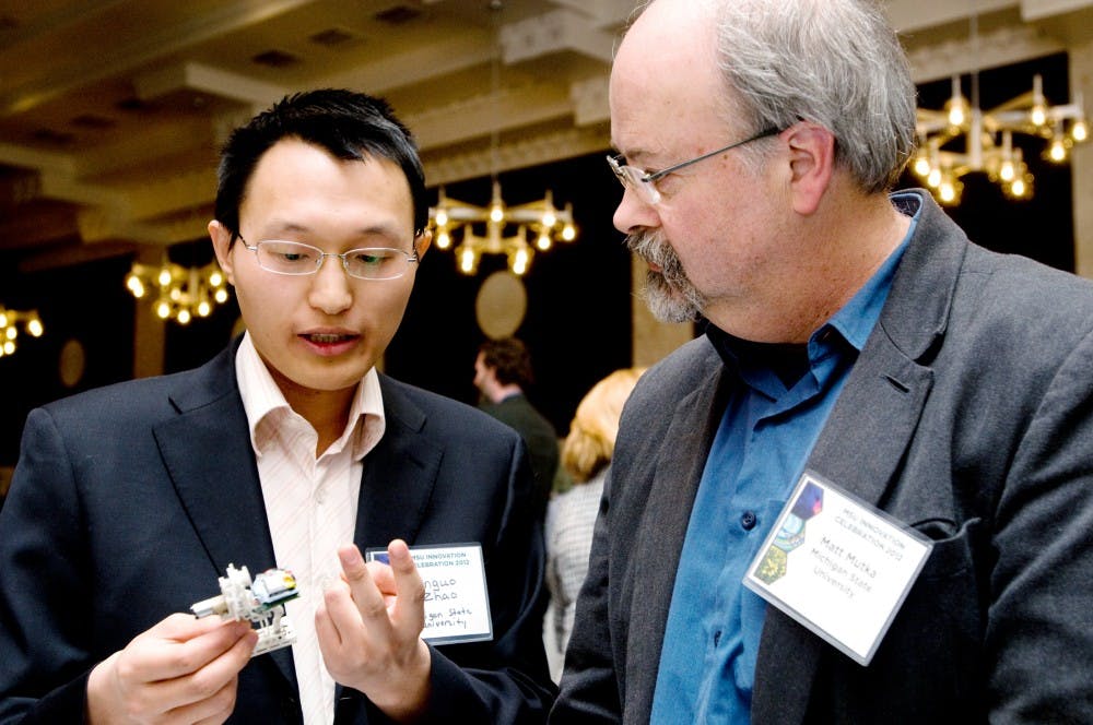 Electrical engineering doctoral student, Jianguo Zhao explains his "Miniature Steerable Jumping Robot"  to chairperson/professor of computer science and engineering, Matt Mutka Wednesday evening in the Ballroom of the MSU Union. MSU Technologies held its second annual MSU Innovation Celebration to showcase technology and projects that had invention disclosures filed with the university during the calender year. Aaron Snyder/The State News.