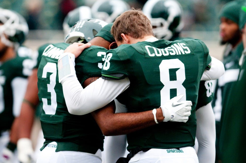 Seniors, quarterback Kirk Cousins, wide receiver B.J. Cunnigham and wide receiver Keshawn Martin huddle together prior to their final home game against Indiana. The Spartans defeated the Hoosiers, 55-3, on Saturday afternoon at Spartan Stadium. Josh Radtke/The State News