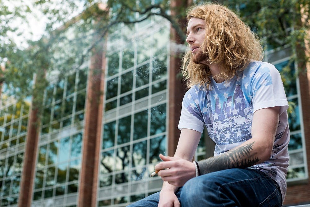 <p>Advertising junior Chris TeBeau takes a cigarette break Sept. 29, 2014, between studying outside of the Main Library. Erin Hampton/The State News</p>