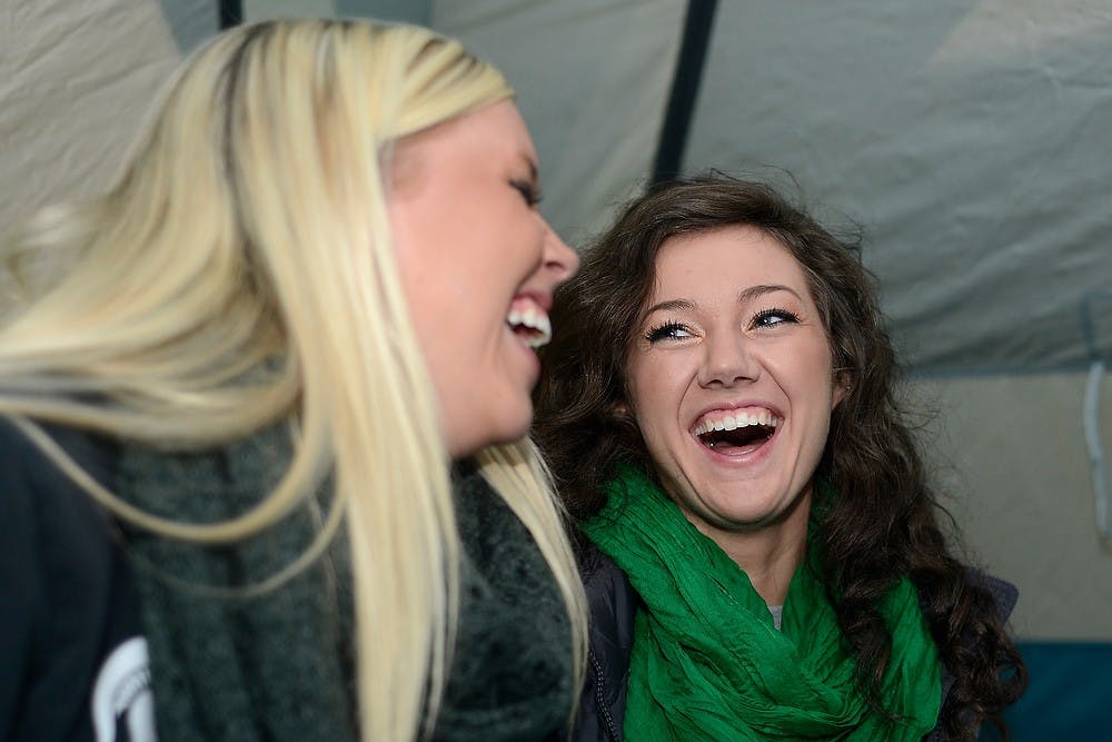 <p>Elementary education junior Anna Ralph, left, and nutritional sciences junior Megan Altizer laugh in their tent Oct. 17, 2014, during the Izzone Campout at Munn Field. Hundreds of students battled the cold and rain to sleep outdoors overnight in hopes of getting lower bowl seating. Julia Nagy/The State News</p>