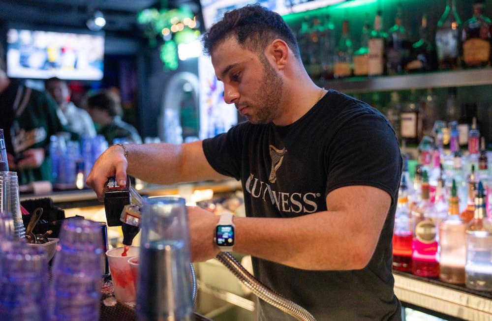 A bartender makes drinks at Landshark Bar & Grill during St. Patrick's day on March 17, 2023. 