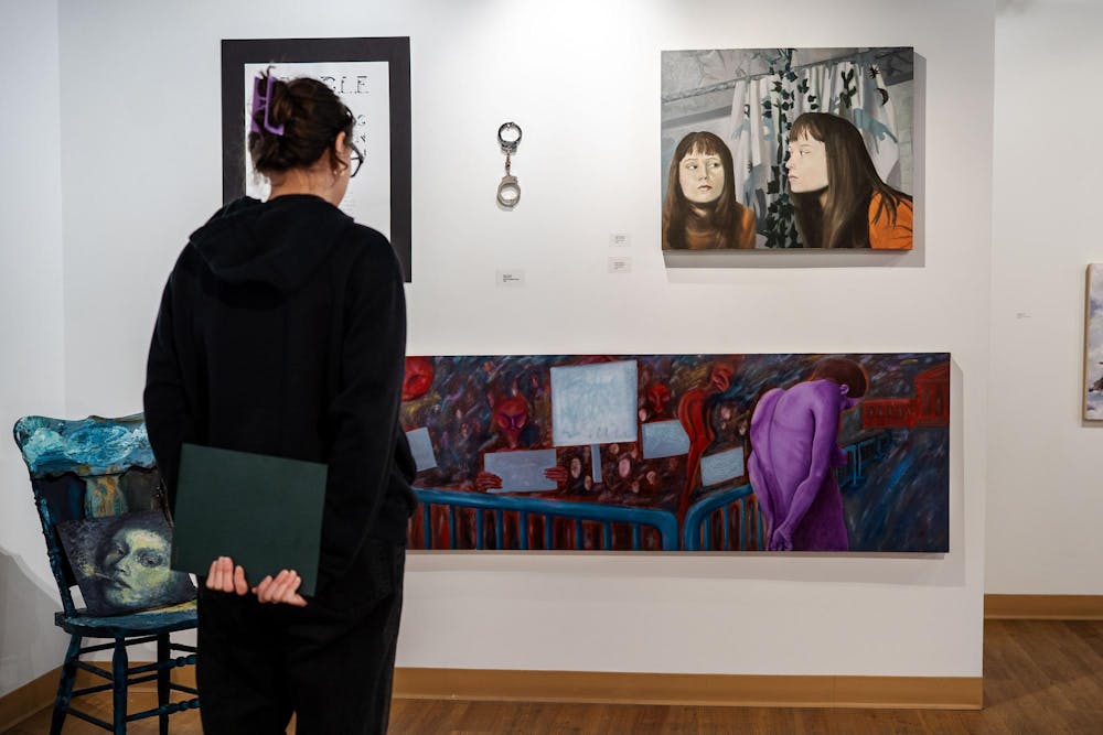 Fourth-year Michigan State studio art student Evan Yalowitz looks at her painting Final Destination at the Scene Metrospace gallery on April 13, 2025. “I knew I wanted a nude female figure to be in the painting, and I needed a reference photo. So one night, I was here in my studio at midnight, completely alone… I locked both doors, set up my camera, and took the photos myself,” Yalowitz said. “I knew it had to be me. If I’m going to put so much of my emotion into this, it can’t be another figure — it has to be me.”