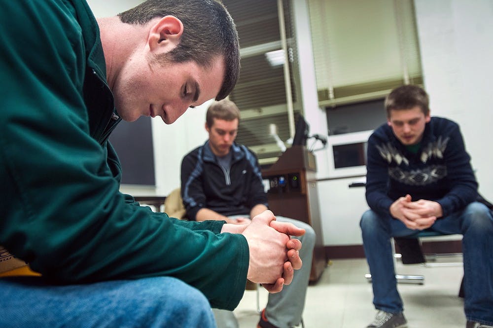 	<p>Physics senior Derik Peterman, left, prays with other students at a Bible-study group Monday, Jan 21, 2013, at Berkey Hall. Peterman is a Catholic and he is interning at the St John Church and Student Center. Justin Wan/The State News</p>