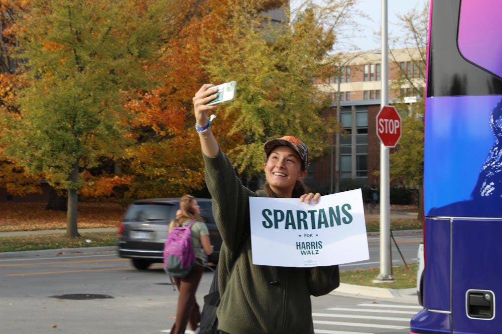 A students takes a selfie with a Spartans for Harris-Walz poster at an early voting rally on Oct. 29, 2024. 