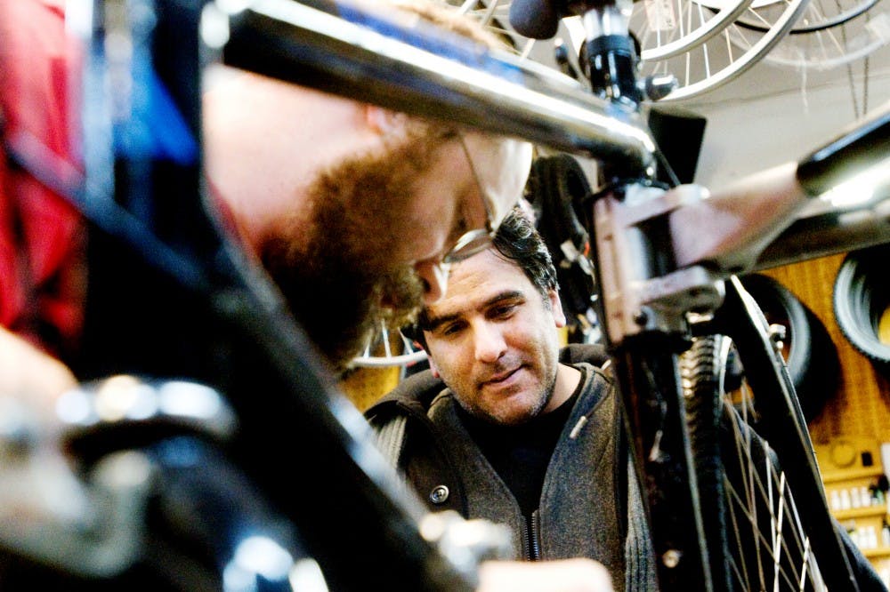 St. John's resident Tony Medina looks on as Don Beach, a mechanic at Denny's Central Park Bicycles, 1805 Central Park Drive, Okemos, checks out the spokes of his bike. Medina recently found his previously stolen bike on eBay after doing a random search of the year and type. Jaclyn McNeal/The State News