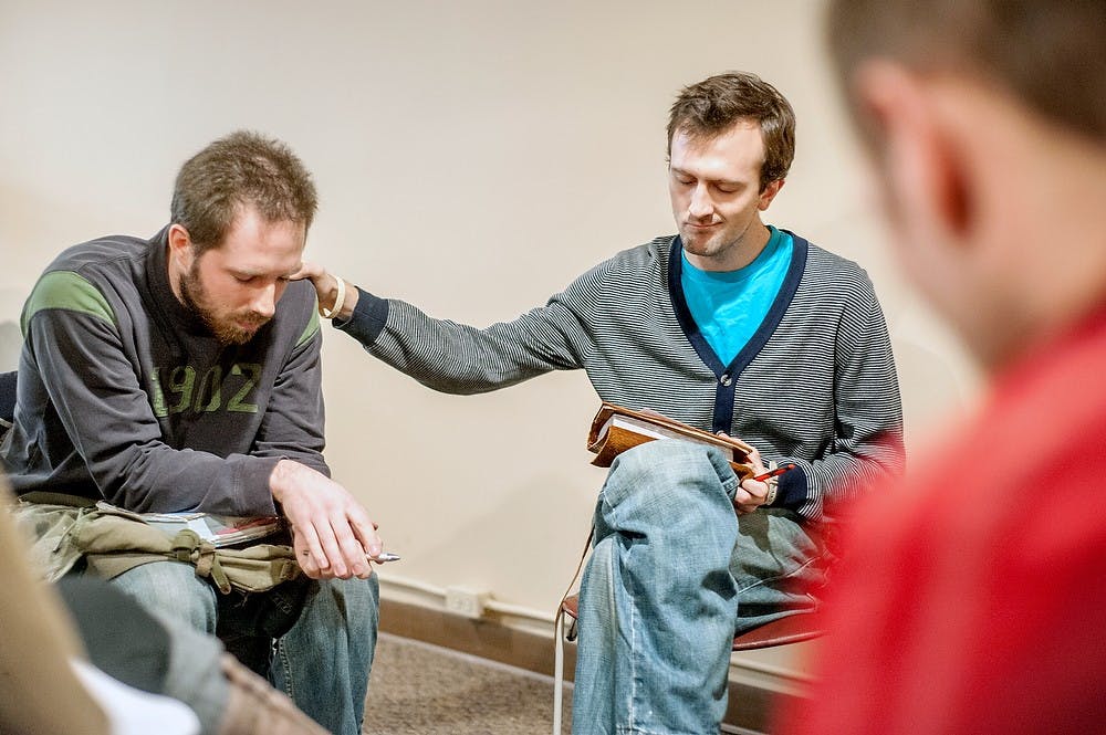 	<p>Garrett Anderson, who teaches at Lansing Christian School, prays for Justin Reid, left, a music theory graduate student, Sunday, Feb. 10, 2013, at The Prayer Room, of 213 1/2 E. Grand River Ave. The location was formerly a record store, but changed to the current usage last semester. Justin Wan/The State News</p>