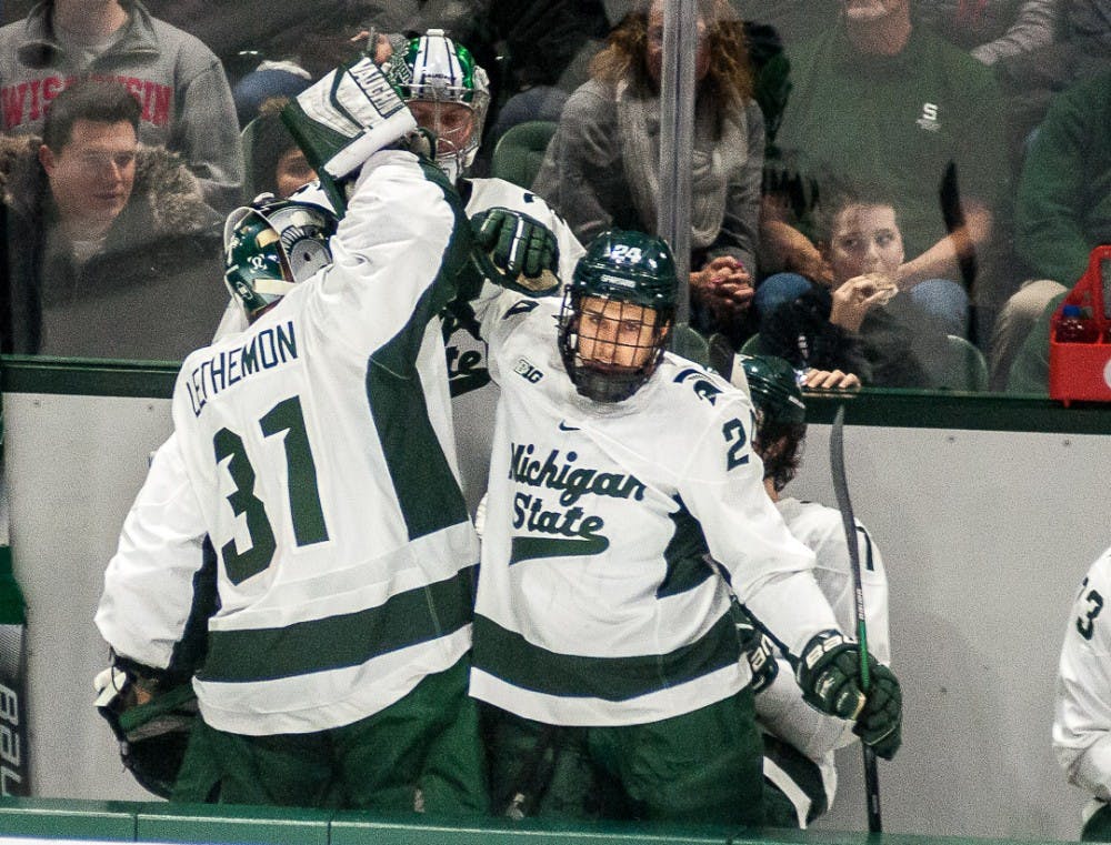 Right wing Austin Kamer (24) and goalie John Lethemon (31) high five during the game against Wisconsin on Feb. 1, 2019 at Munn Ice Arena. The Spartans lead the Badgers, 3-1 at the end of the second period.