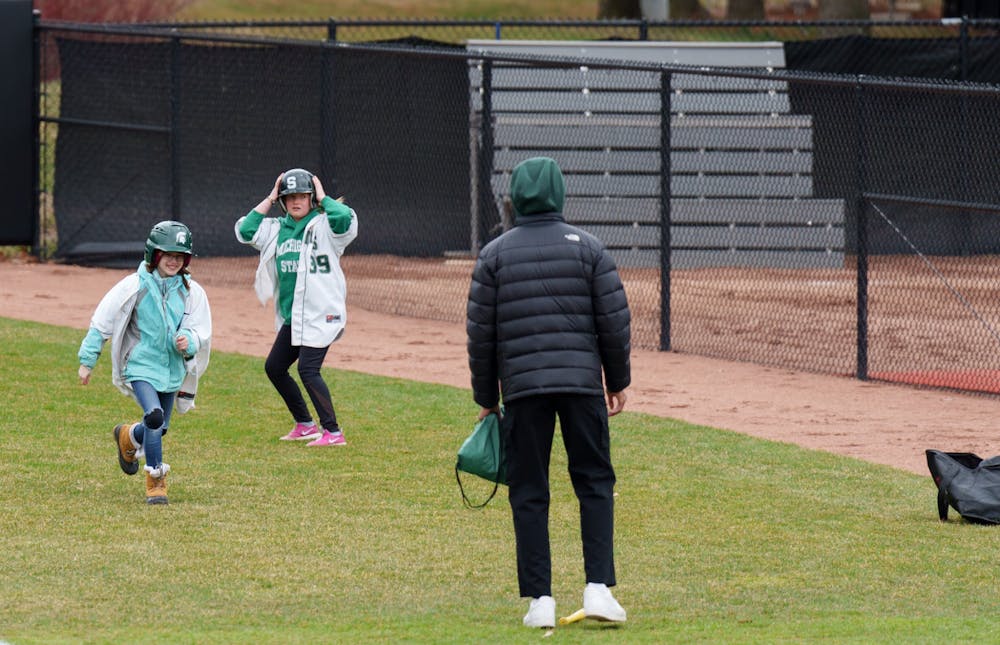 <p>Between innings, two kids spun around a bat, threw on a Spartan jersey and raced to a Spartan helmet in the grass and back. This was a part of the “Dress like a Spartan” challenge. Spartans lost 6-0 against Nebraska, on April 9, 2022.</p>