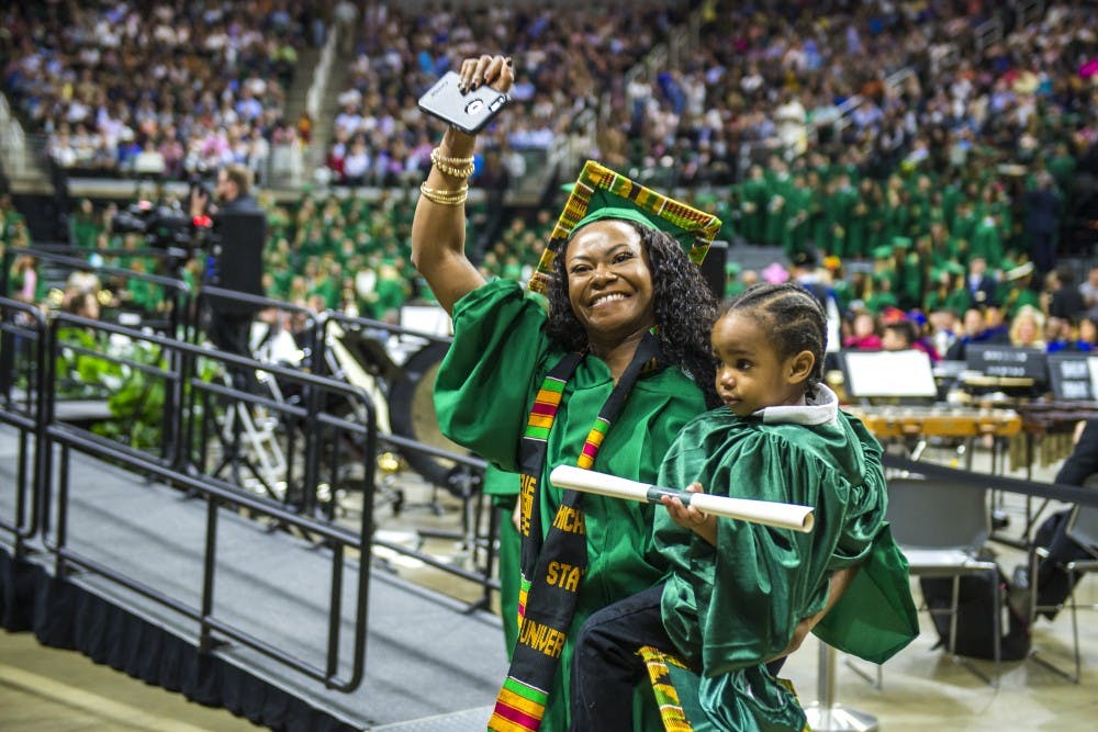 Brittany raises her fist after crossing the stage with Logan to receive her diploma during the Social Science Convocation on May 5, 2018 at Breslin Center. "I can't believe I did it," Brittany said. "I can't believe I did it with Logan. It's amazing, I don't even know how to put it in words. I don't think it's hit me yet that I'm done. It's just surreal."