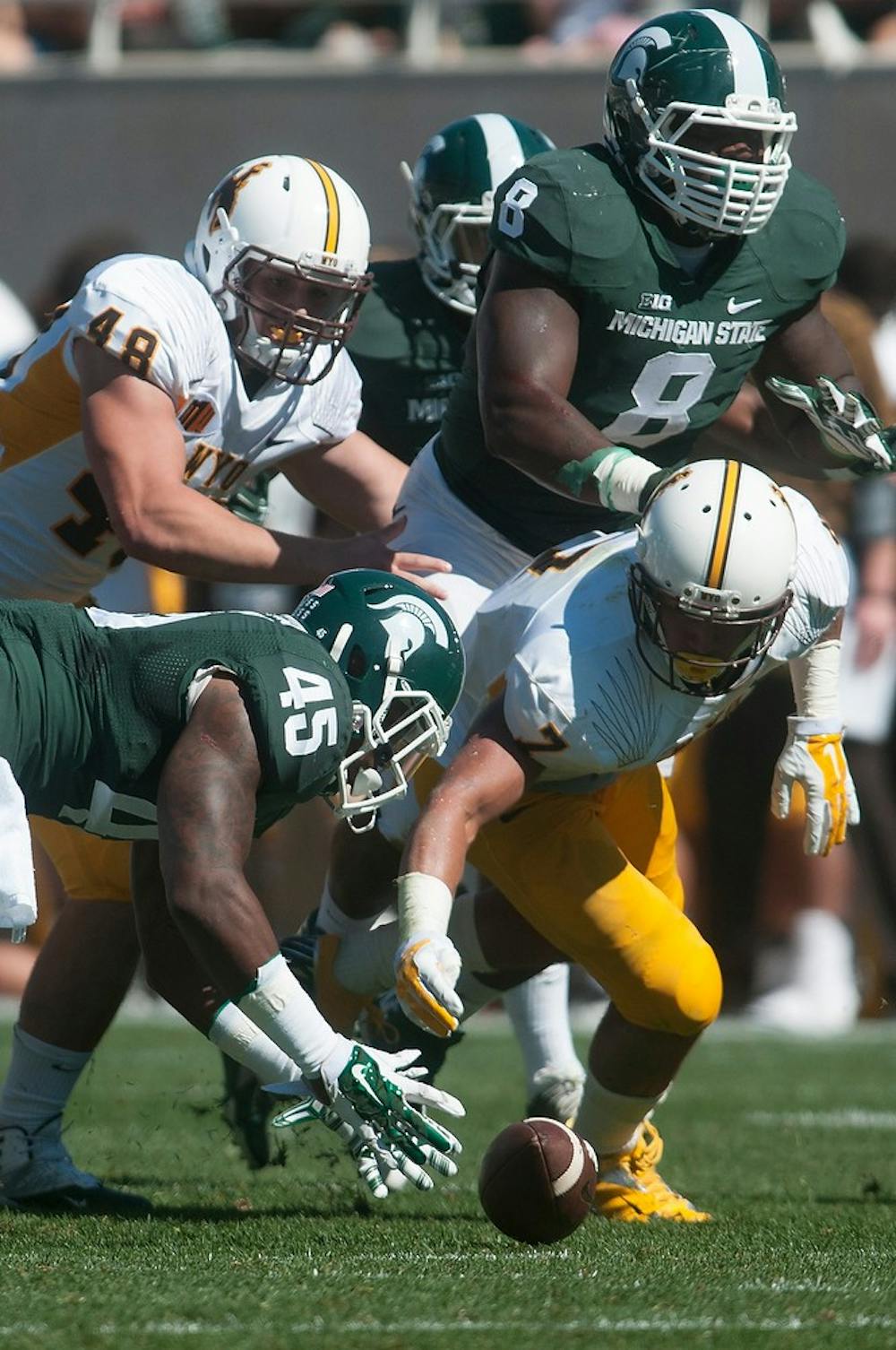 <p>Junior linebacker Darien Harris and Wyoming running back D.J. May dive to recover a Wyoming fumble Sept. 27, 2014, at Spartan Stadium. The Spartans lead at halftime, 42-14. Julia Nagy/The State News</p>