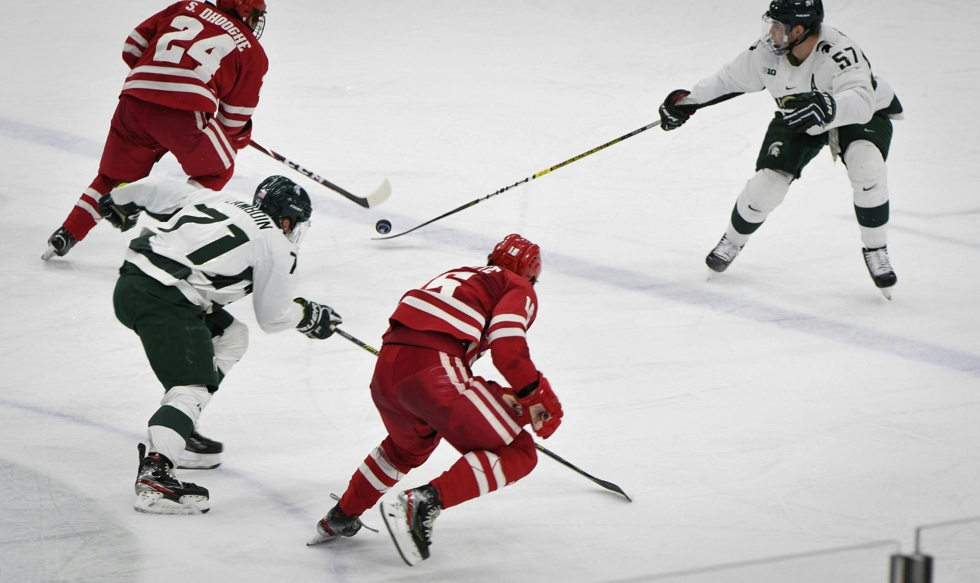 <p>Redshirt senior defender Jerad Rosburg (57) and senior forward Logan Lambdin (71) fight for the puck during the game against Wisconsin at the Munn Ice Arena on Dec. 6, 2019. The Spartans defeated the Badgers 3-0.</p>