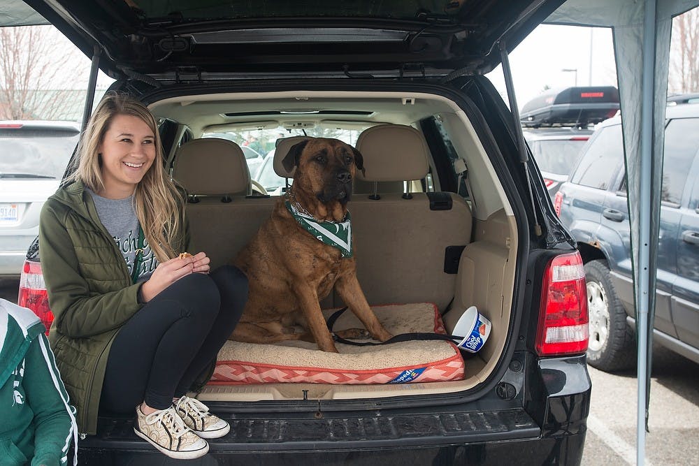 <p>Communication senior Samantha Mahaffy sits next to her dog Hooch at a tailgate prior the Green and White Spring  Game April 25, 2015, at Spartan Stadium. The white team defeated the green team, 9-3. Hannah Levy/The State News</p>