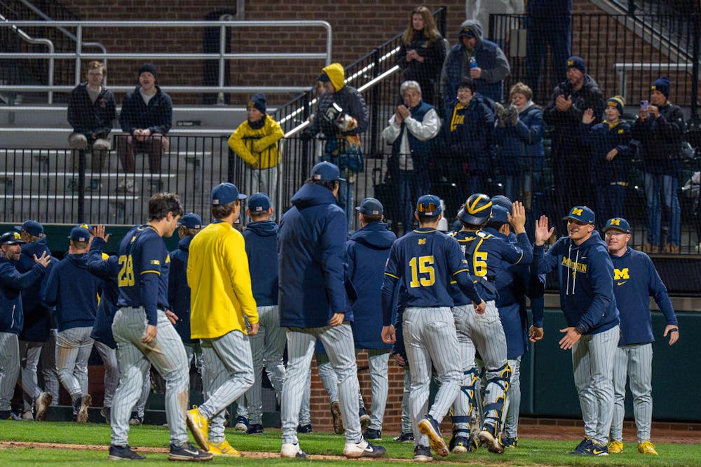 Michigan teammates smile and high-five one another after their victory against Michigan State during Michigan's game against Michigan State at Jeff Ishbia Field at McLane Stadium in East Lansing, Mich., on Friday, April 10, 2026.