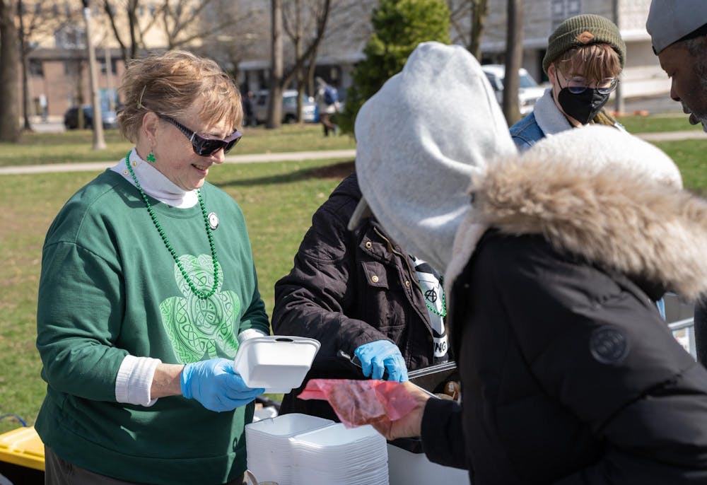 <p>Punks with Lunch volunteer, Lianne Thiel, left, serves stew and cookies to a community member at Reutters Park on March 16, 2024. Thiel's cookies are one of many baked goods served at the organization's outreach events.</p>