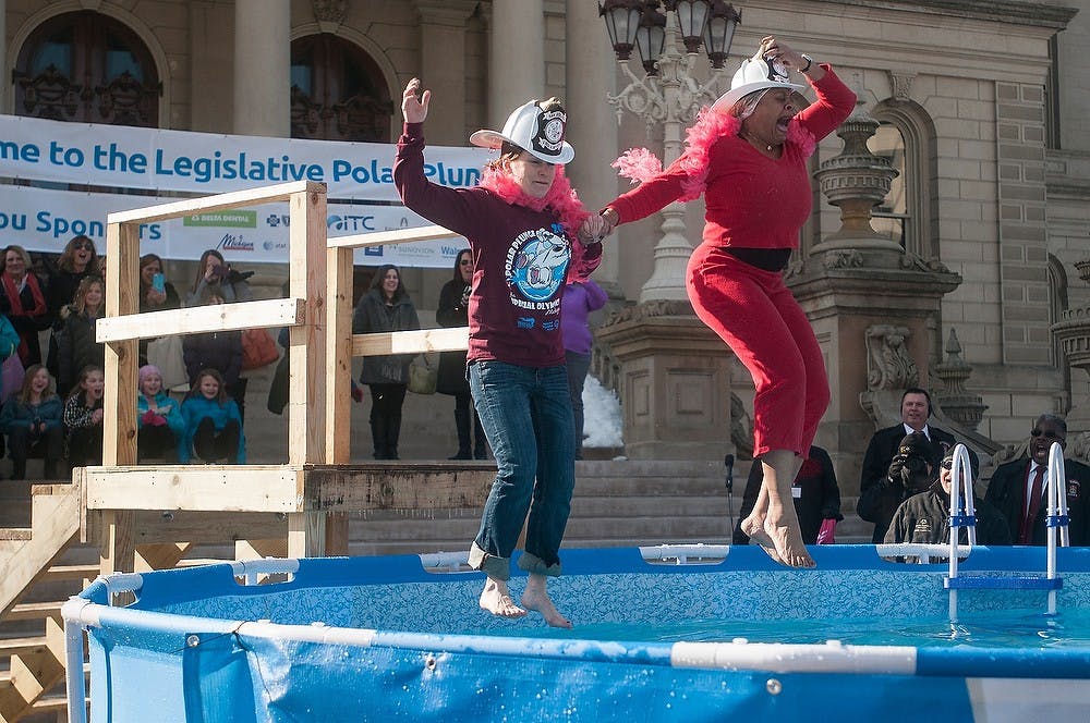<p>Lobbyist and organizer of the Legislative Polar Plunge Melissa Yutzey, left, and State Representative Leslie Love jump into a freezing pool together March 5, 2015, in front of the Capitol Building in Downtown Lansing for the annual Polar Plunge fundraiser for Special Olympics.</p>