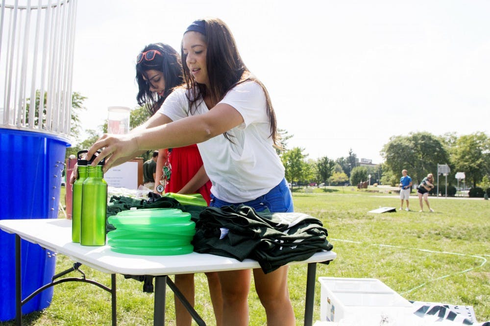 Senior marketing major and Cheif of Staff, Katio Gross and sophmore hospitality business major and Director of Communications and Event Planning, Kiran Samara set up a table full of prizes and free gifts during the ASMSU kickoff meeting Monday afternoon at Valley Court Park. ASMSU hosted a meeting along with an afternoon filled with games and a dunk tank to raise money for charity. Aaron Snyder/The State News.