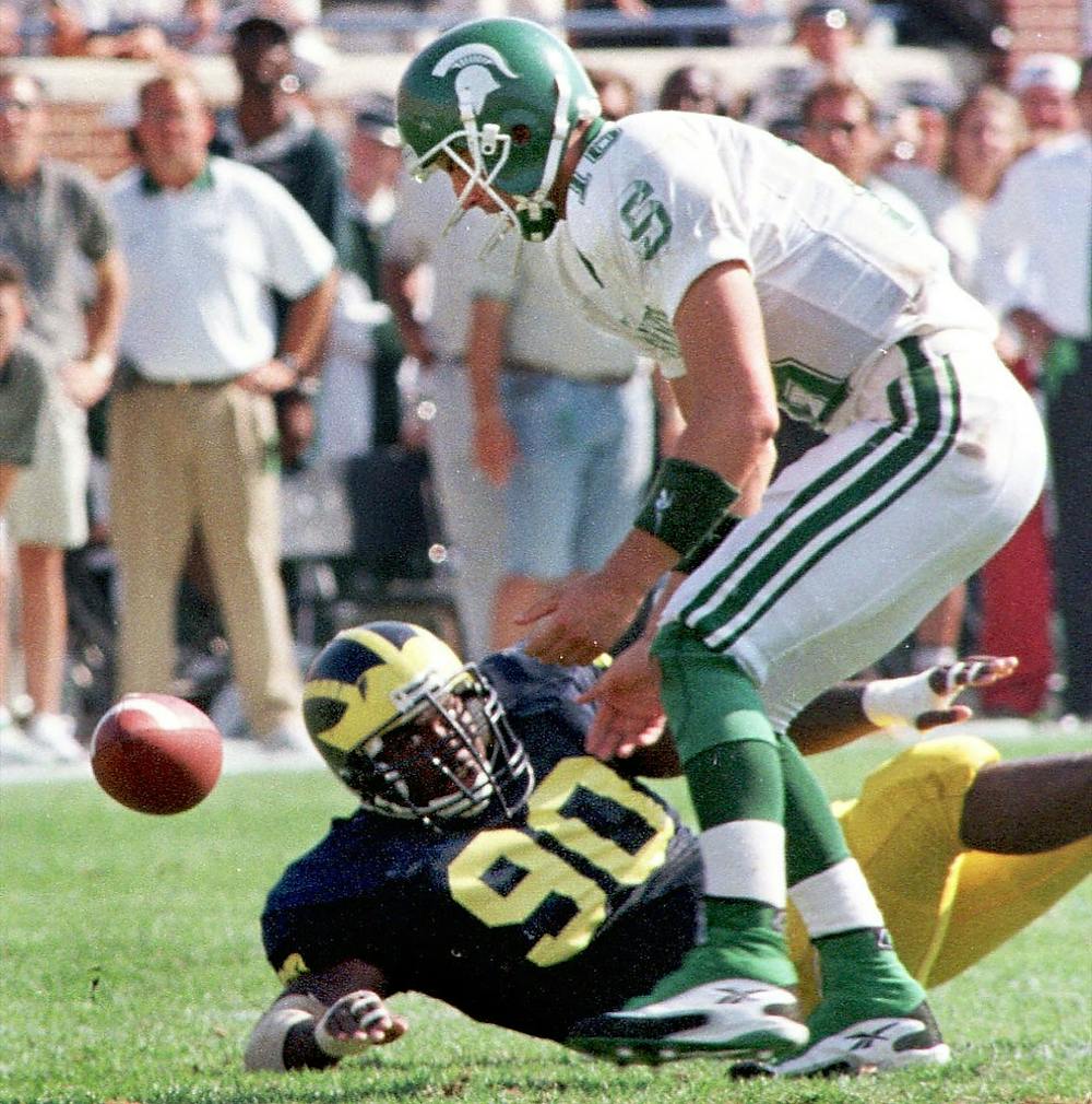 <p>Junior quarterback Bill Burke tries to pick up the football near Michigan's Juaquin Feazell on Sept. 26, 1998, at Michigan Stadium in Ann Arbor. The Spartans lost, 29-17. Cory Morse/The State News</p>