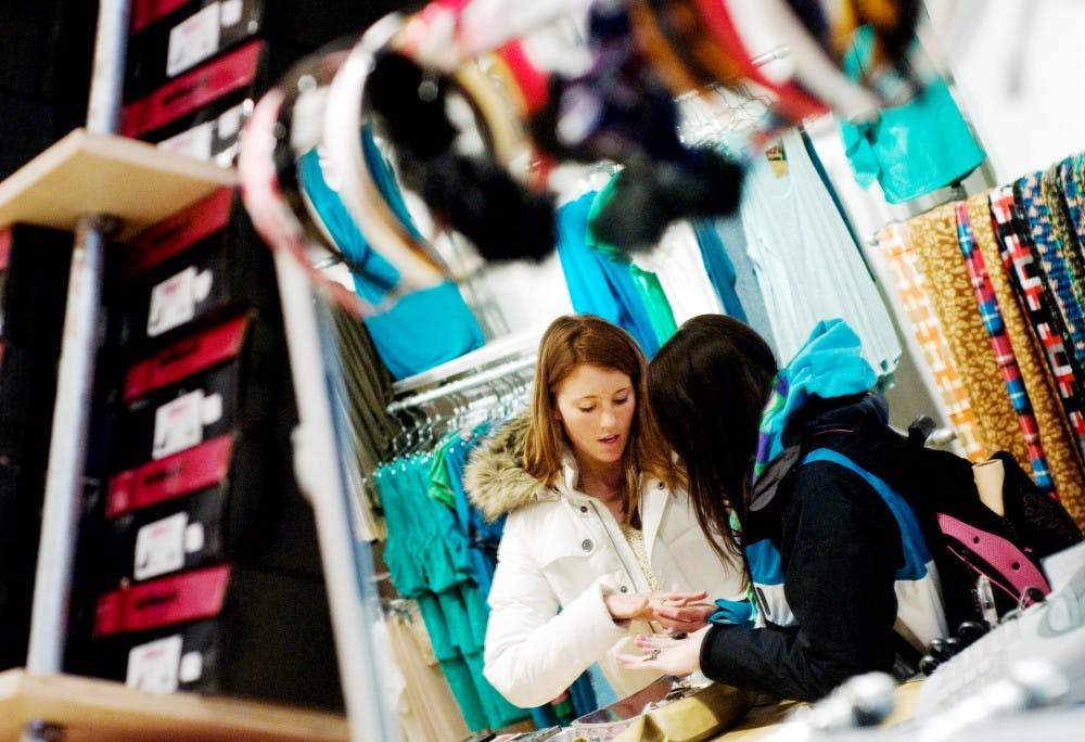 Interior design sophomores Samantha Kosek, left, and Kate Duerksen try on rings Thursday at Pitaya, 213 E. Grand River Ave. Thursday was Kosek's birthday and the pair were shopping for outfits for her party. Pitaya officially opened for business on Monday. Kat Petersen/The State News