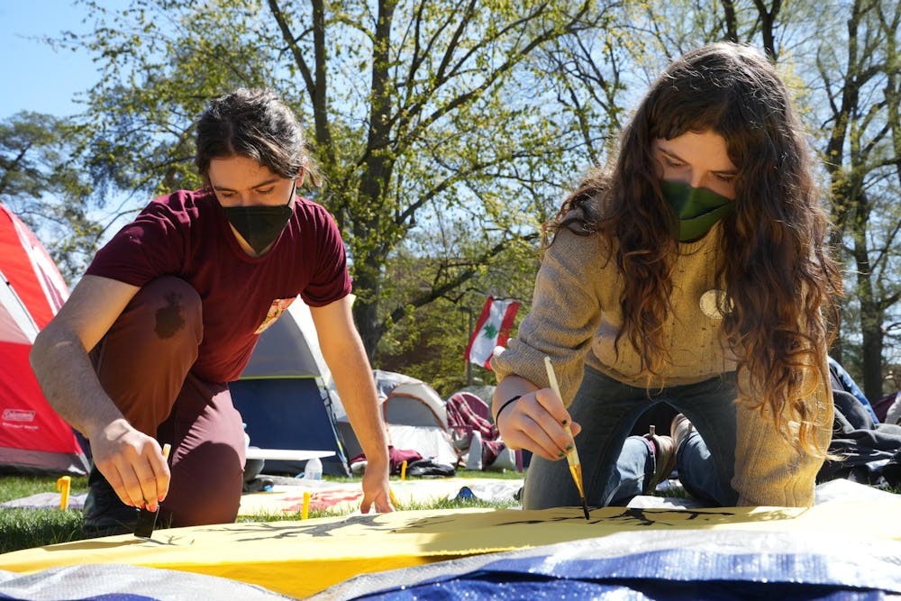<p>Two students paint trees on a banner during a Gaza solidarity encampment in People’s Park behind Wells Hall on April 25, 2024.</p>