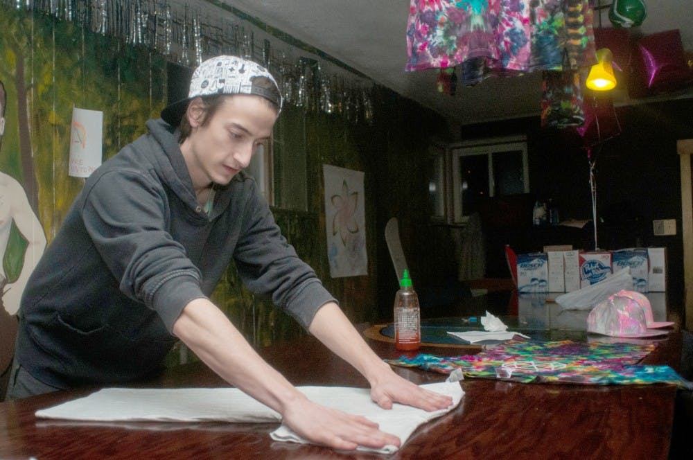 Computer engineering senior Craig Stoddard folds a shirt on Feb. 26, 2016 at his home in East Lansing. Stoddard makes tie dye shirts when he is not in class or studying and sells them online. 