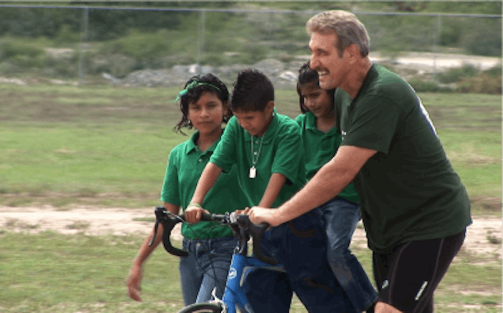 <p>Former MSU football defensive lineman John Shinsky helps children during the 2,000 Mile Bike for the Orphanage in 2009. Photo courtesy of John Shinsky.</p>
