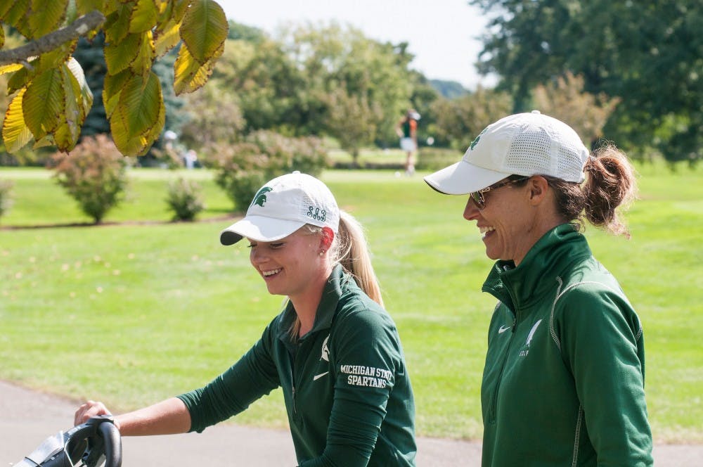 Women's golf head coach Stacy Slobodnik, right, talks with junior Sarah Burnham before a shot on Sept. 25, 2016 at Forest Akers West Golf Course. Slobodnik has held the head coaching position at MSU for 19 years. 