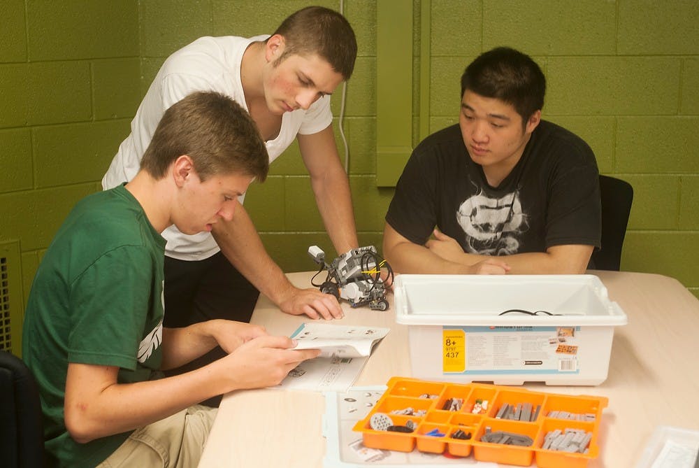 	<p>From left to right, mechanical engineering sophomore Trevor Ploucha, chemical engineering sophomore John Zaidel and electrical engineering sophomore Yuxiang Zhou work on their first major design project Sept. 10, 2013, in Engineering 100 in Wilson Hall. The goal is to build an autonomous robot that can do tasks to simulate a real-world factory setting. Margaux Forster/The State News</p>