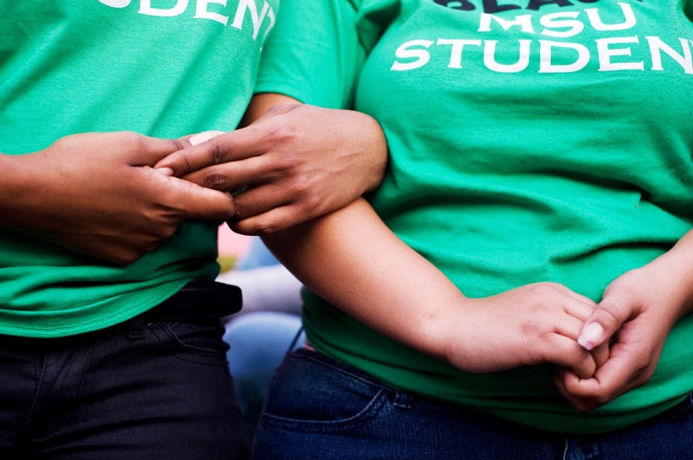 Journalism junior Silver Moore, left, links arms with special education junior Genel Fowler during the protest rally hosted by the Black Student Alliance and Iota Phi Theta fraternity on Thursday evening in reaction to a string on racial incidents that occurred on campus within the past week. Several hundred students marched from Brody Complex before stopping behind Akers Hall for the rally. Lauren Wood/The State News