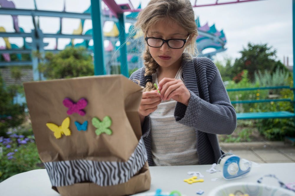 East Lansing resident Juliet Ivkovich, 7, decorates a hat during the Mad Hatter Tea Party on June 28, 2016 at the 4-H Children's Garden. Ivkovich said she was decorating her hat tea party style.