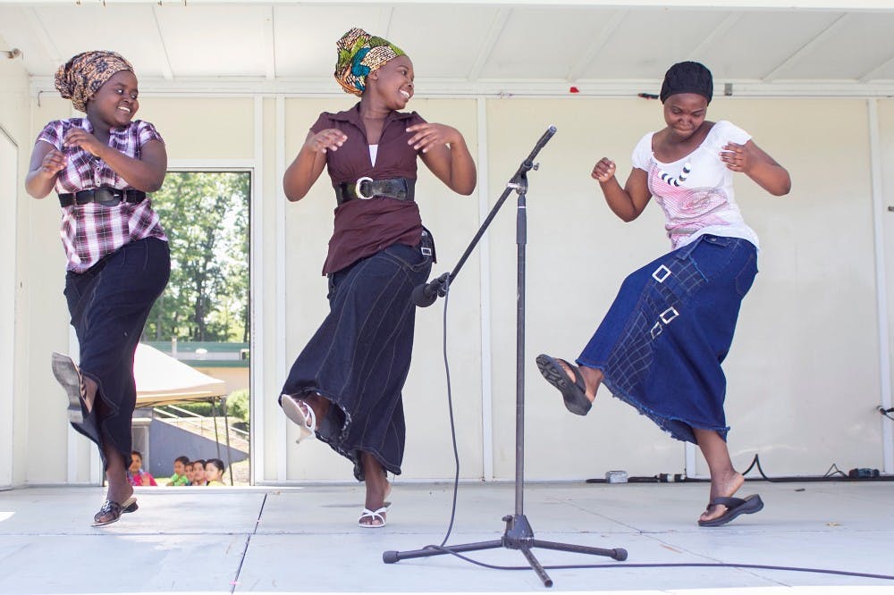 Burundian Choir members Toyi Eline, left, Minani Esperanca, middle, and Esta Kabura sing and dance during World Day at Hunter Park. World Day featured activities like arts and crafts and garden house tours, among others.