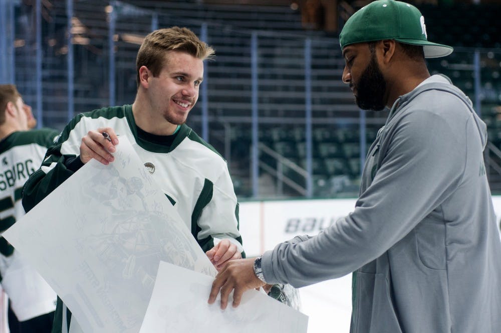 <p>Freshman defenseman Zach Osburn signs an autograph for Haslett, Mich., resident Ed Tillett during a meet and greet with the MSU Men's Hockey team on Nov. 16, 2015 in Munn Ice Arena. Tillett went to MSU as an undergraduate and graduate student and currently works in the Career Services Center. He said that he's been an MSU fan for his entire life. </p>