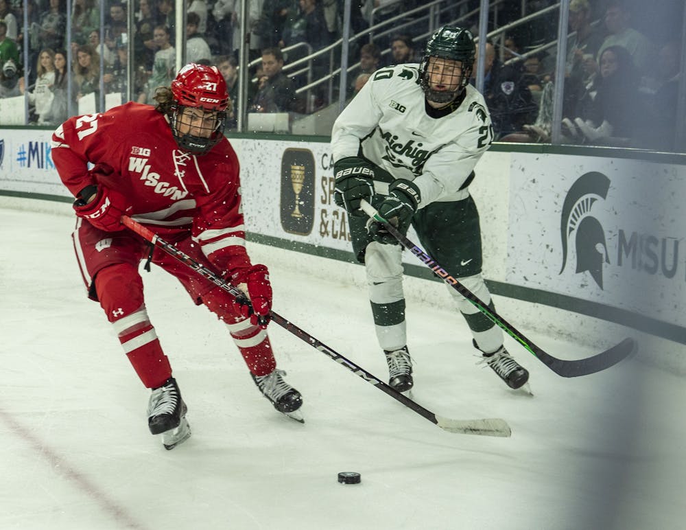 <p>Freshman forward Daniel Russell (20) fights for the puck during a game of ice hockey between MSU and Wisconsin at Munn Ice Arena on Nov. 4, 2022. The Spartans won, 5-0.</p>